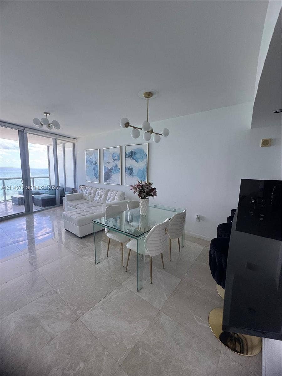 Open-concept interior featuring large-format tile flooring, floor-to-ceiling glass sliding doors, and modern multi-arm globe chandeliers