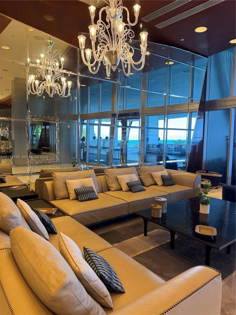 Floor-to-ceiling glass curtain walls, expansive wall-to-wall mirrored paneling, decorative multi-tiered chandelier, and polished dark ceiling finish