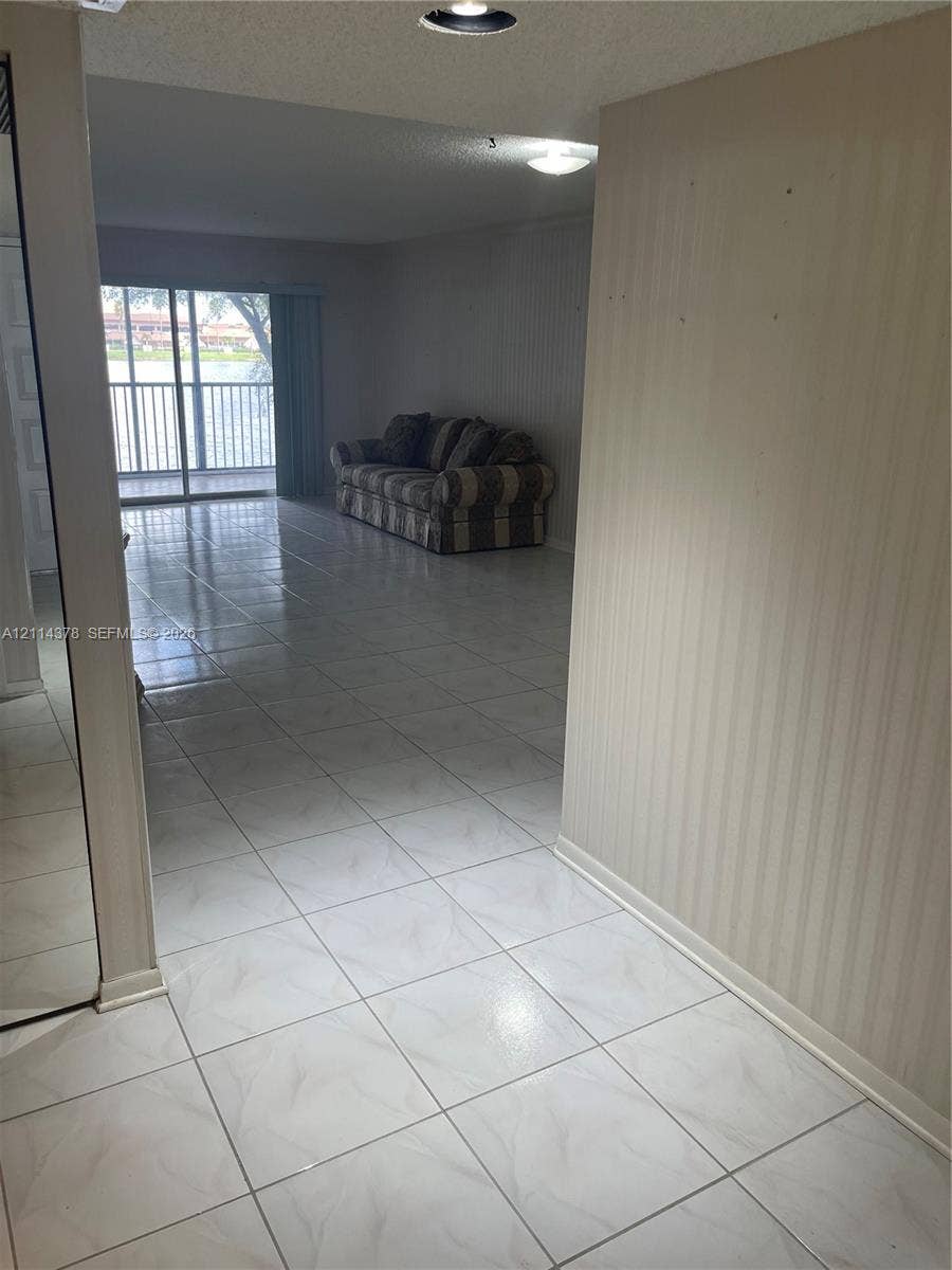 13355 SW 16th Court, #205E, Pembroke Pines, FL 33027 Interior space featuring large-format tile flooring, textured wallpaper, recessed lighting, and a sliding glass door providing external access
