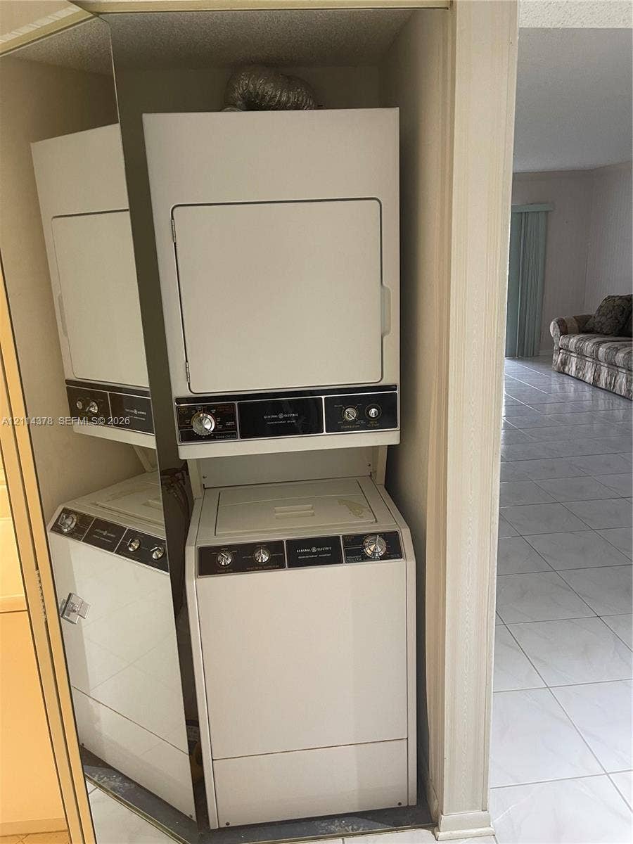 13355 SW 16th Court, #205E, Pembroke Pines, FL 33027 Stacked white laundry appliance unit housed within a closet featuring mirrored bi-fold doors