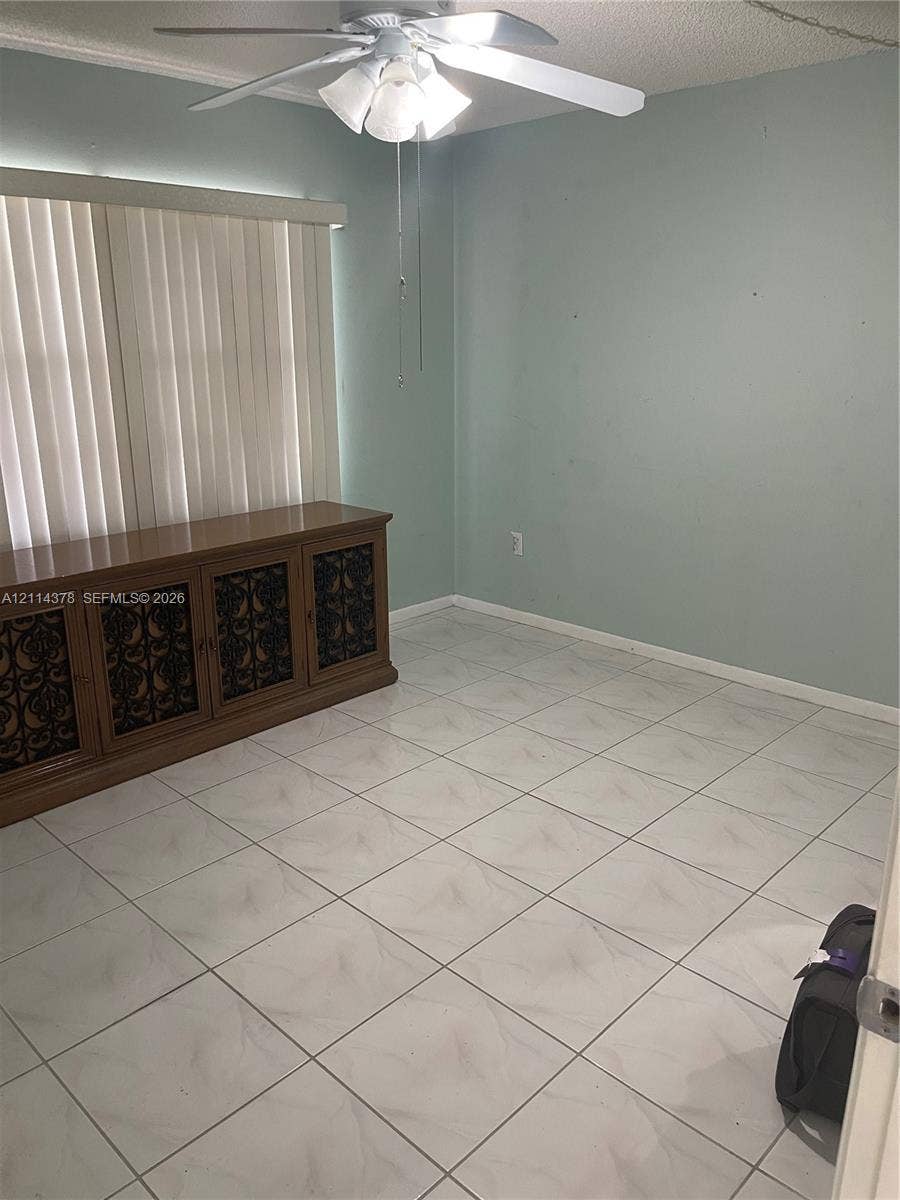 13355 SW 16th Court, #205E, Pembroke Pines, FL 33027 Room featuring large-format tile flooring, a multi-blade ceiling fan with integrated light fixture, and horizontal window blinds