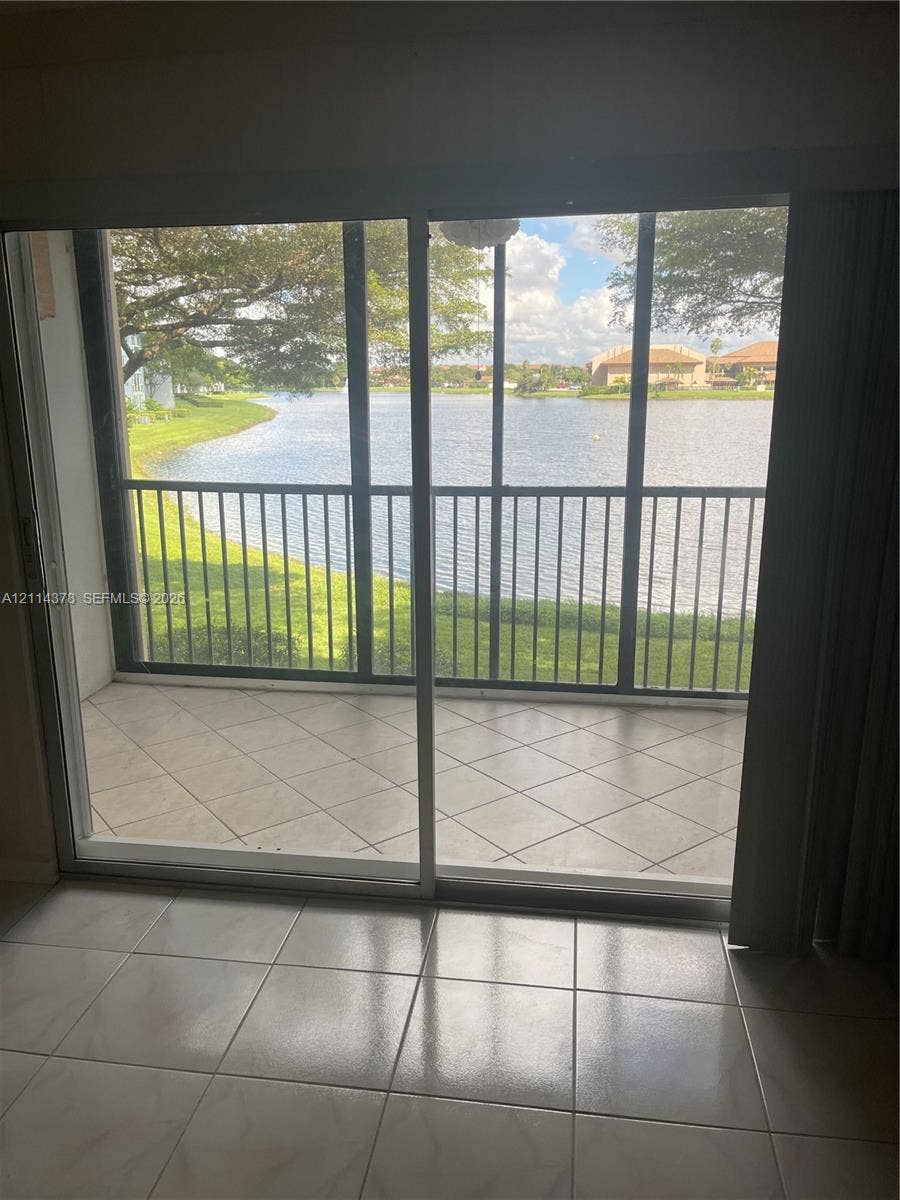 13355 SW 16th Court, #205E, Pembroke Pines, FL 33027 Screened-in balcony featuring tile flooring, metal railings, and direct water frontage