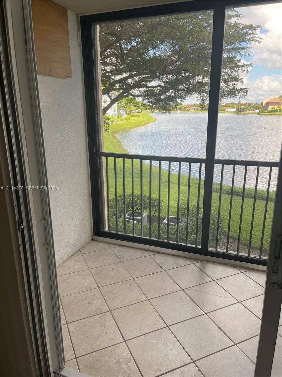 13355 SW 16th Court, #205E, Pembroke Pines, FL 33027 Screened-in balcony featuring ceramic tile flooring, metal railings, and exposure to a water feature