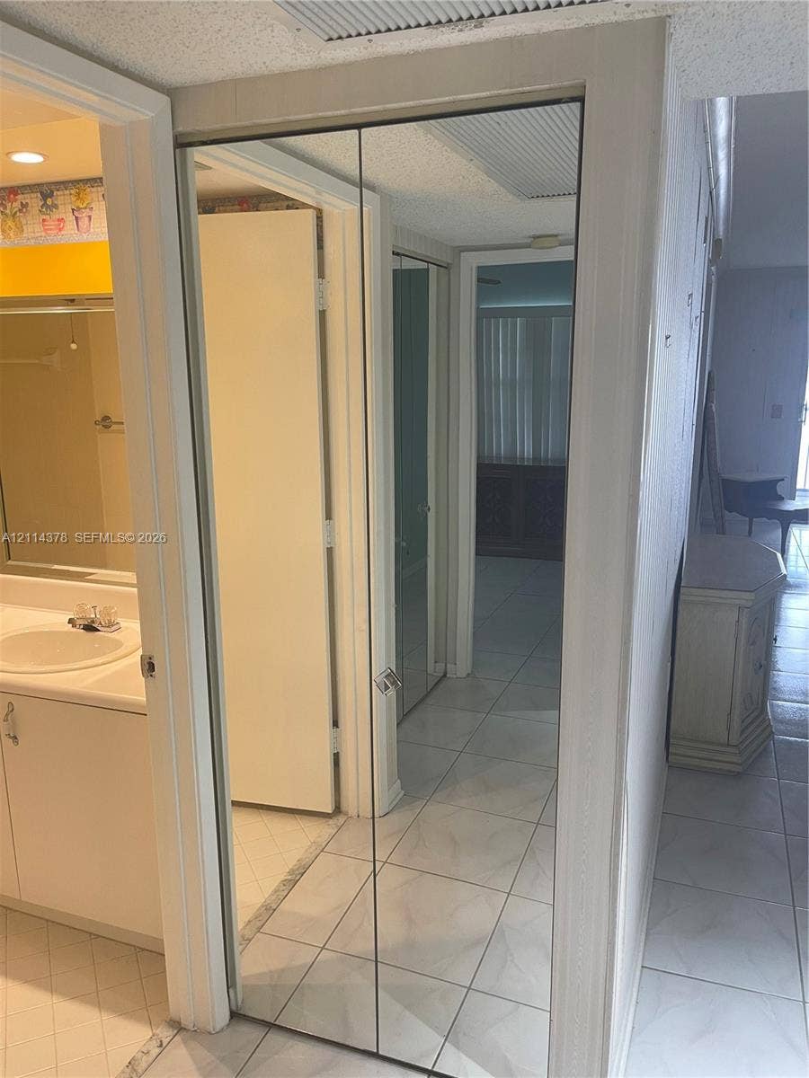 13355 SW 16th Court, #205E, Pembroke Pines, FL 33027 Full-length mirrored bifold closet doors featuring brushed metallic trim and integrated hardware