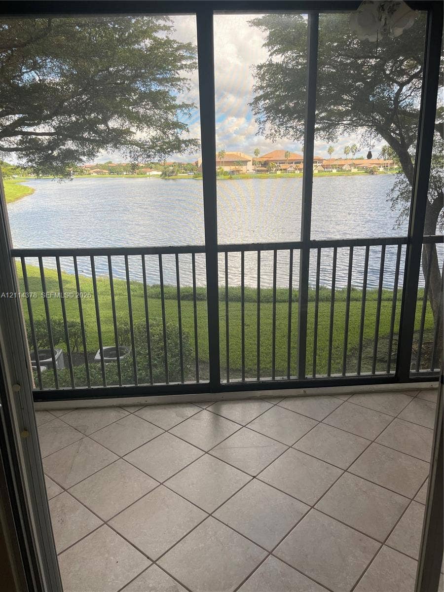 13355 SW 16th Court, #205E, Pembroke Pines, FL 33027 Screened-in patio with neutral tile flooring, metal frame enclosures, and water frontage