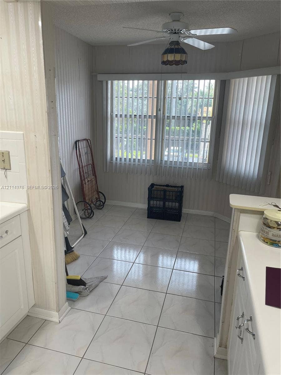 13355 SW 16th Court, #205E, Pembroke Pines, FL 33027 Ceramic tile flooring, bay window with vertical blinds, and a ceiling-mounted light fixture with a fan