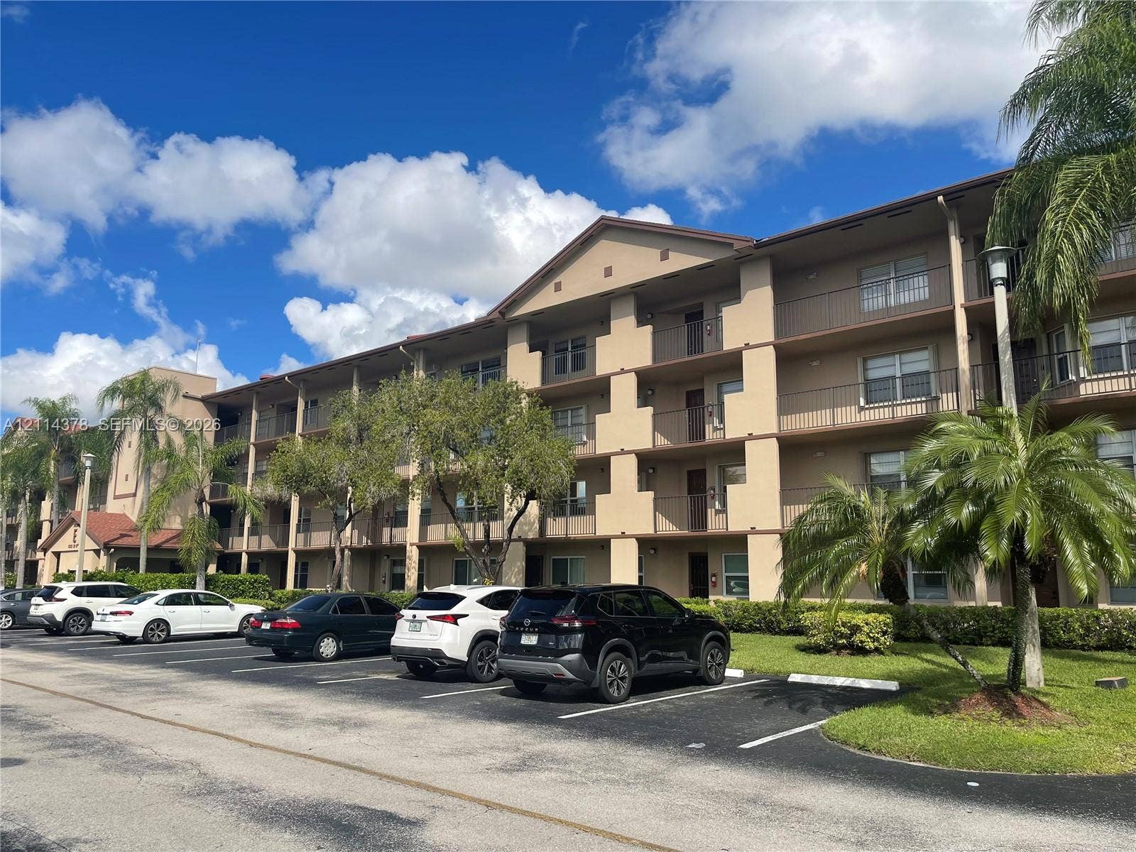 13355 SW 16th Court, #205E, Pembroke Pines, FL 33027 Multi-story building exterior featuring stucco siding, gabled roofline, and private balconies with metal railings