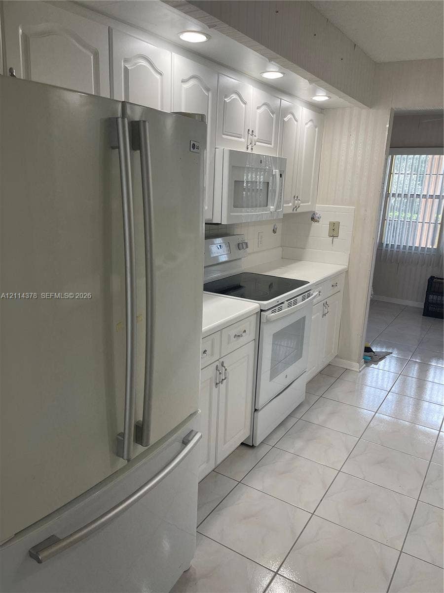 13355 SW 16th Court, #205E, Pembroke Pines, FL 33027 Kitchen featuring white cabinetry, tile flooring, recessed lighting, and white appliances including a built-in microwave and French-door refrigerator