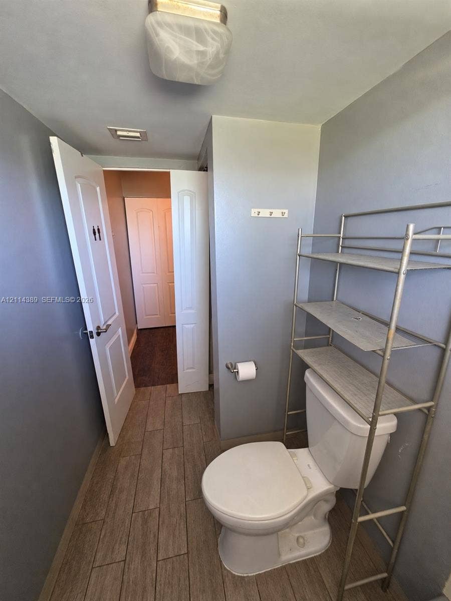 1801 NW 75th Avenue, #301, Plantation, Plantation, FL 33313 Wood-finish tile flooring, white porcelain toilet, and ceiling-mounted flush light fixture