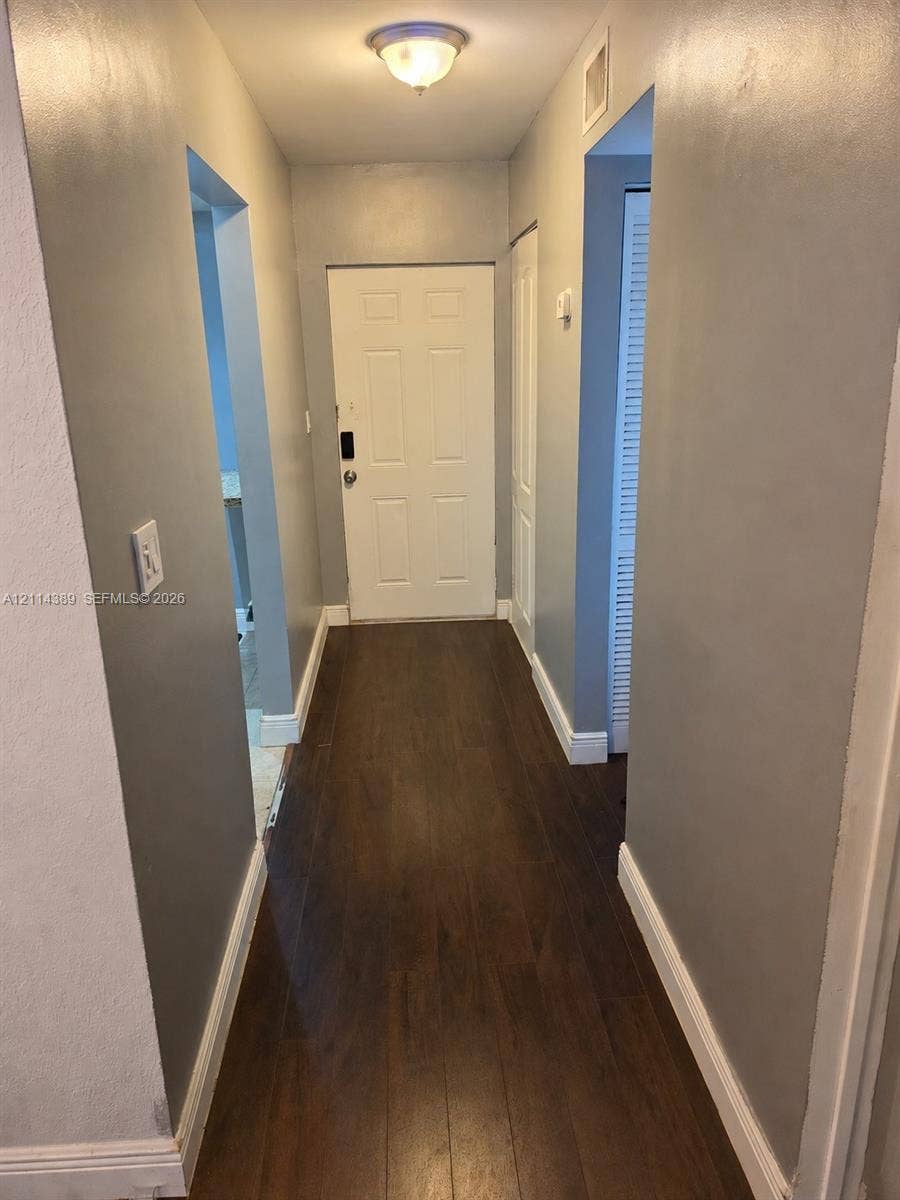 1801 NW 75th Avenue, #301, Plantation, Plantation, FL 33313 Entryway featuring wood-finish flooring, a six-panel door, neutral wall paint, and a flush-mount ceiling light