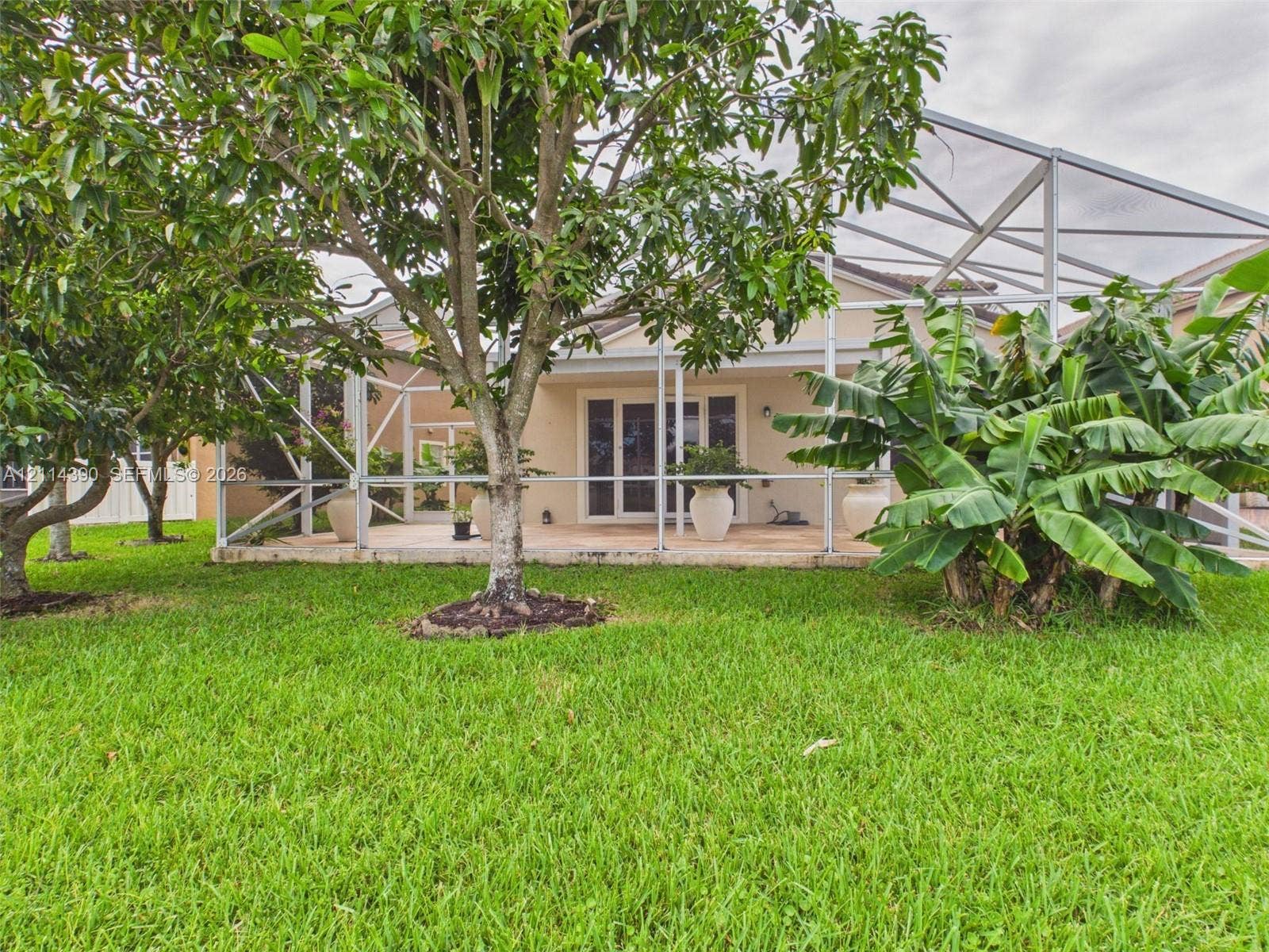 21196 Via Ventura, Boca Raton, FL 33433 Screen-enclosed patio featuring a paver surface, established trees, and mature landscaping