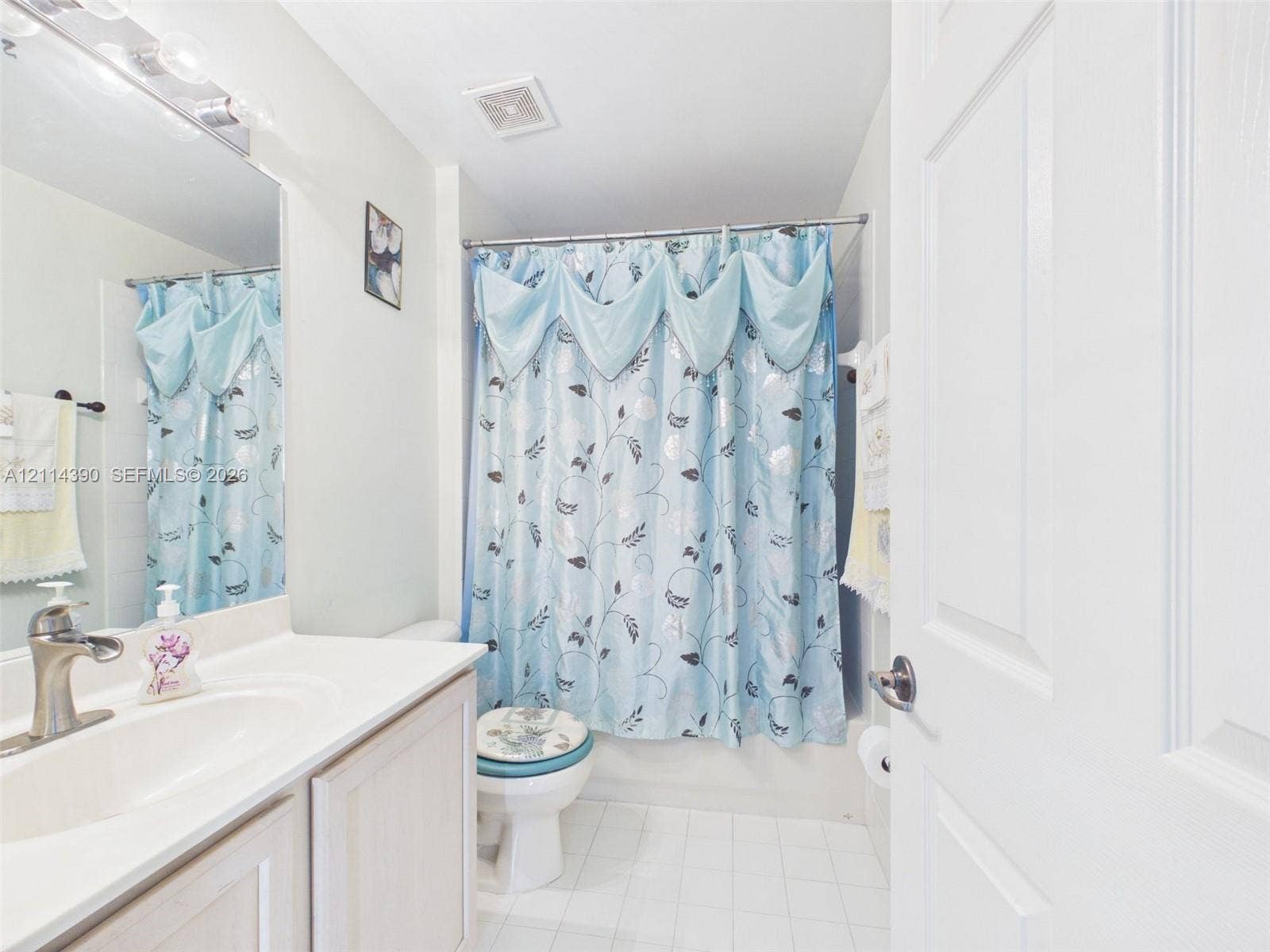21196 Via Ventura, Boca Raton, FL 33433 Bathroom featuring a vanity with an integrated sink, polished metal faucet, wide-frame wall mirror, and tile flooring