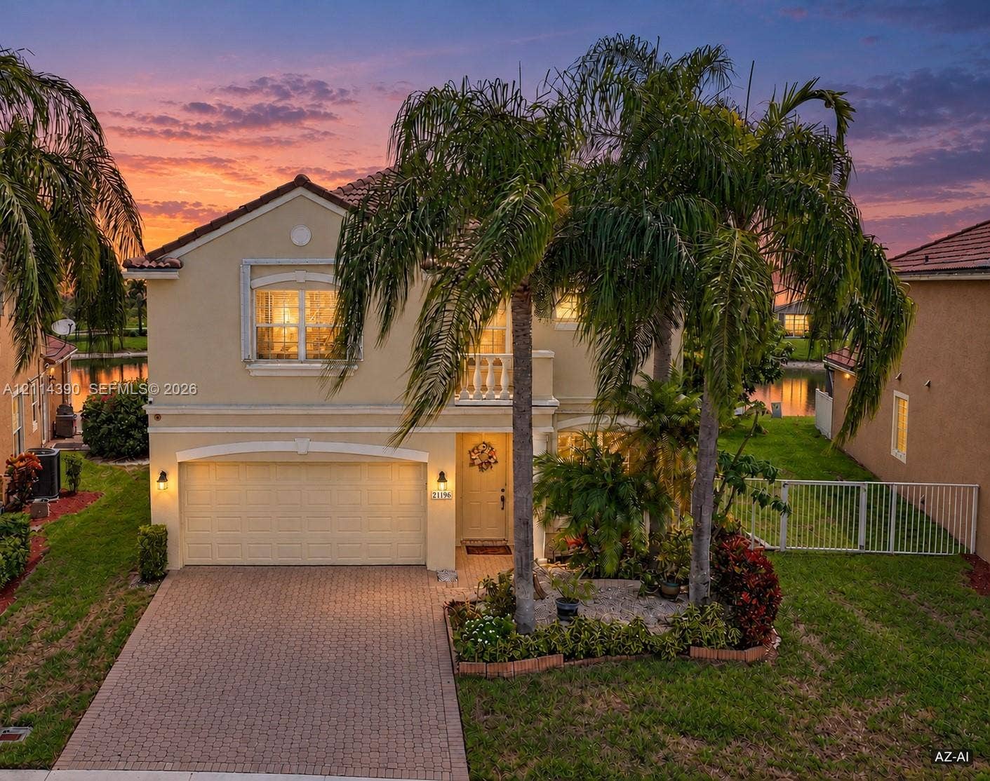 21196 Via Ventura, Boca Raton, FL 33433 Two-story residence featuring a stucco exterior, paver driveway, second-story balcony with balustrade, attached two-car garage, and mature palm landscaping