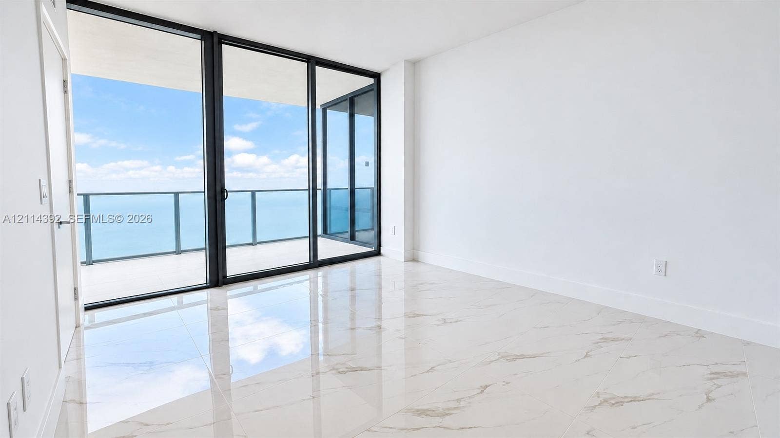 Floor-to-ceiling sliding glass doors, oversized tile flooring, and a glass-paneled balcony