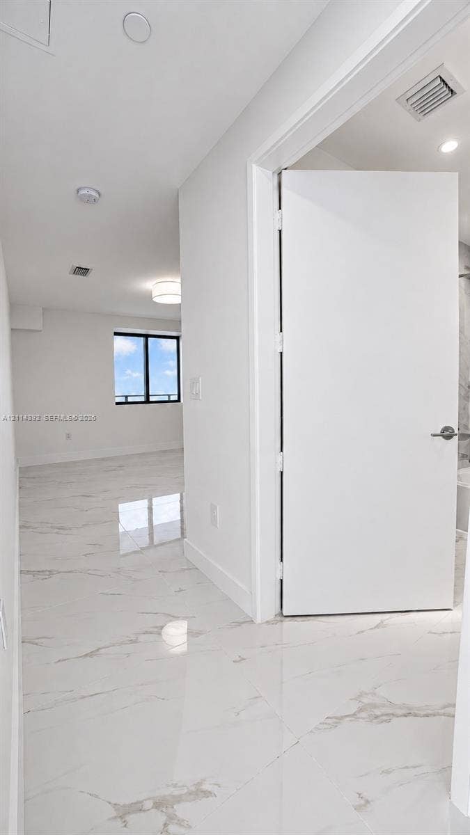 Large-format stone-finish tile flooring, minimalist solid-core interior door, and recessed lighting