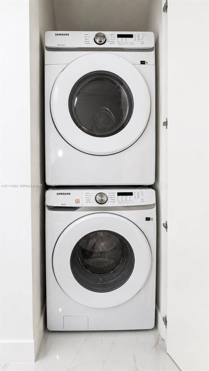 Stacked white Samsung front-loading laundry units housed within a dedicated closet