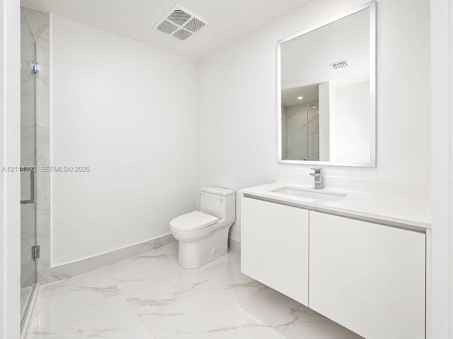 Modern bathroom featuring a floating vanity with a seamless countertop, rectangular sink, polished-edge mirror, and floor-to-ceiling tiled shower with a frameless glass door