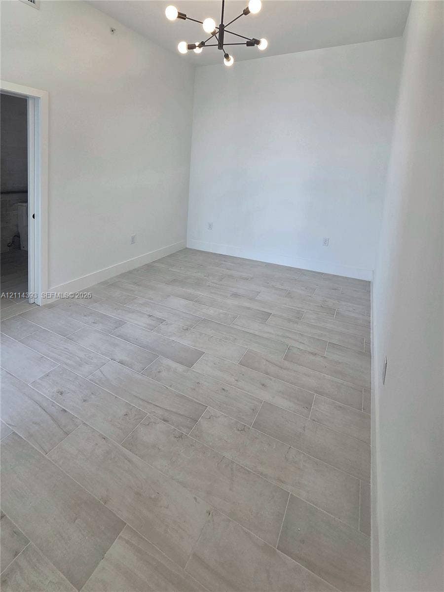 401 Pembroke Road, #202, Hallandale Beach, Hallandale Beach, FL 33009 Room interior featuring light-toned tile flooring, neutral walls, and a modern multi-arm light fixture