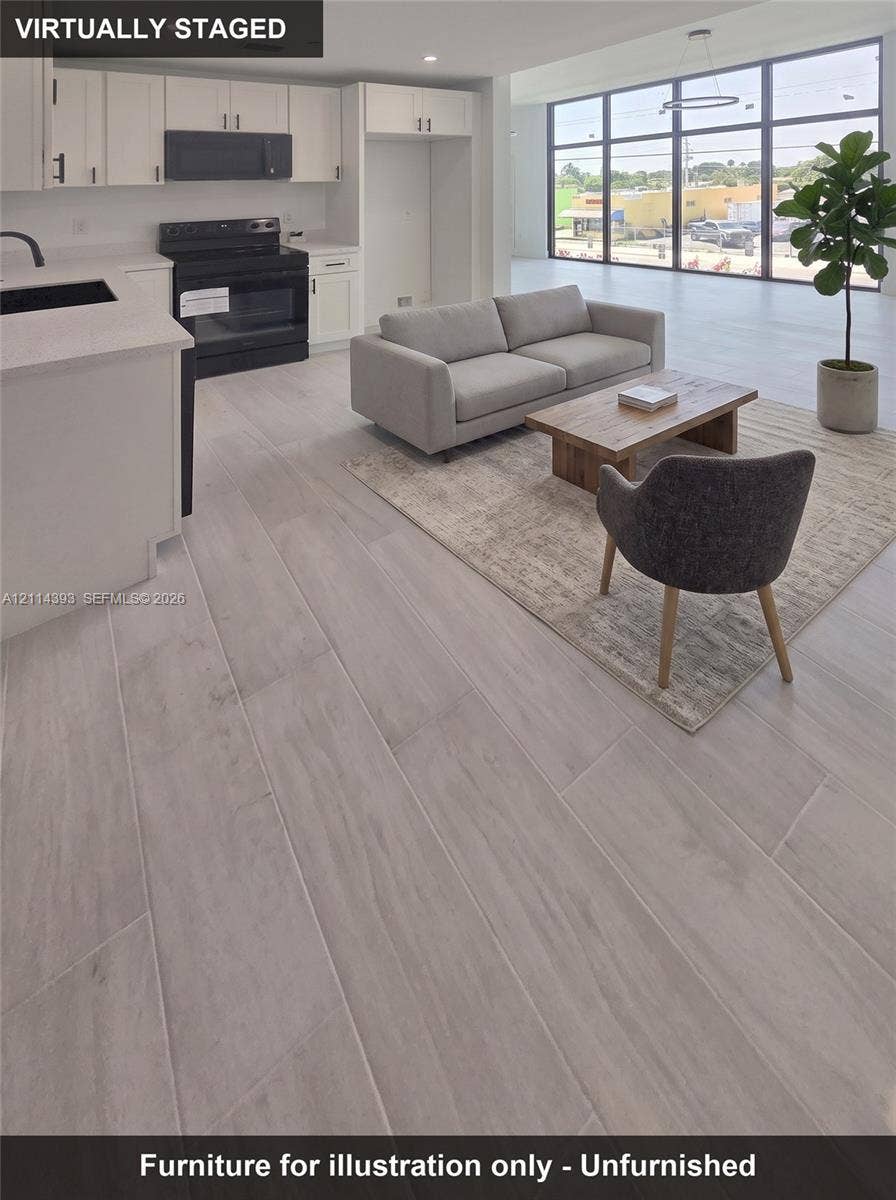 401 Pembroke Road, #202, Hallandale Beach, Hallandale Beach, FL 33009 Kitchen featuring white cabinetry, solid-surface countertops, and black built-in appliances, complemented by wood-finish tile flooring and floor-to-ceiling windows