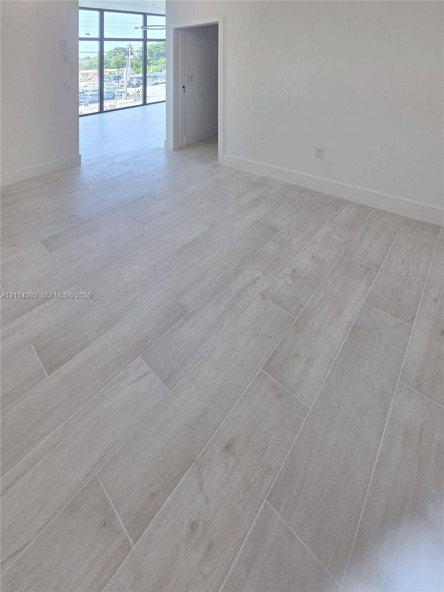 401 Pembroke Road, #202, Hallandale Beach, Hallandale Beach, FL 33009 Interior space featuring wood-finish tile flooring, neutral wall tones, and floor-to-ceiling multi-pane glass panels