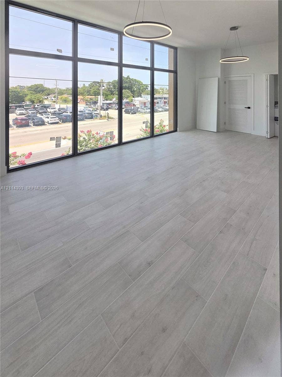 401 Pembroke Road, #202, Hallandale Beach, Hallandale Beach, FL 33009 Floor-to-ceiling windows featuring black framing, wood-finish flooring, and minimalist circular pendant lighting