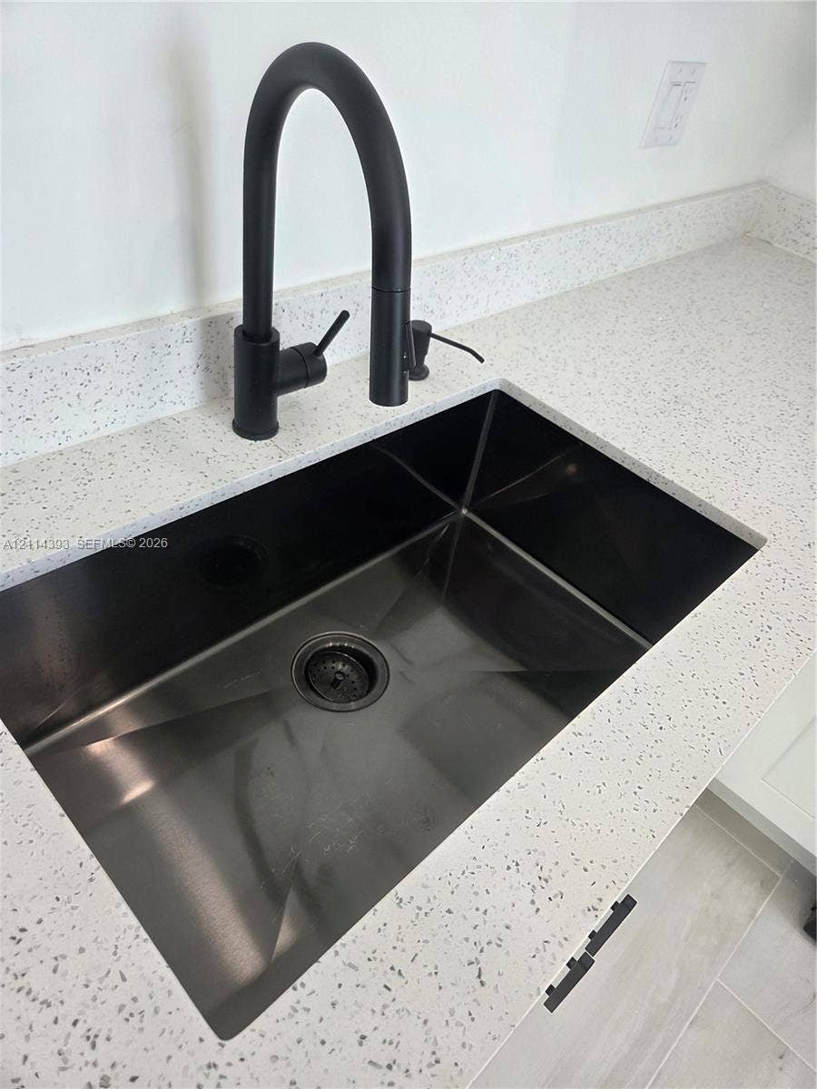 401 Pembroke Road, #202, Hallandale Beach, Hallandale Beach, FL 33009 Undermount stainless steel sink featuring a matte black high-arc gooseneck faucet paired with a speckled stone-finish countertop