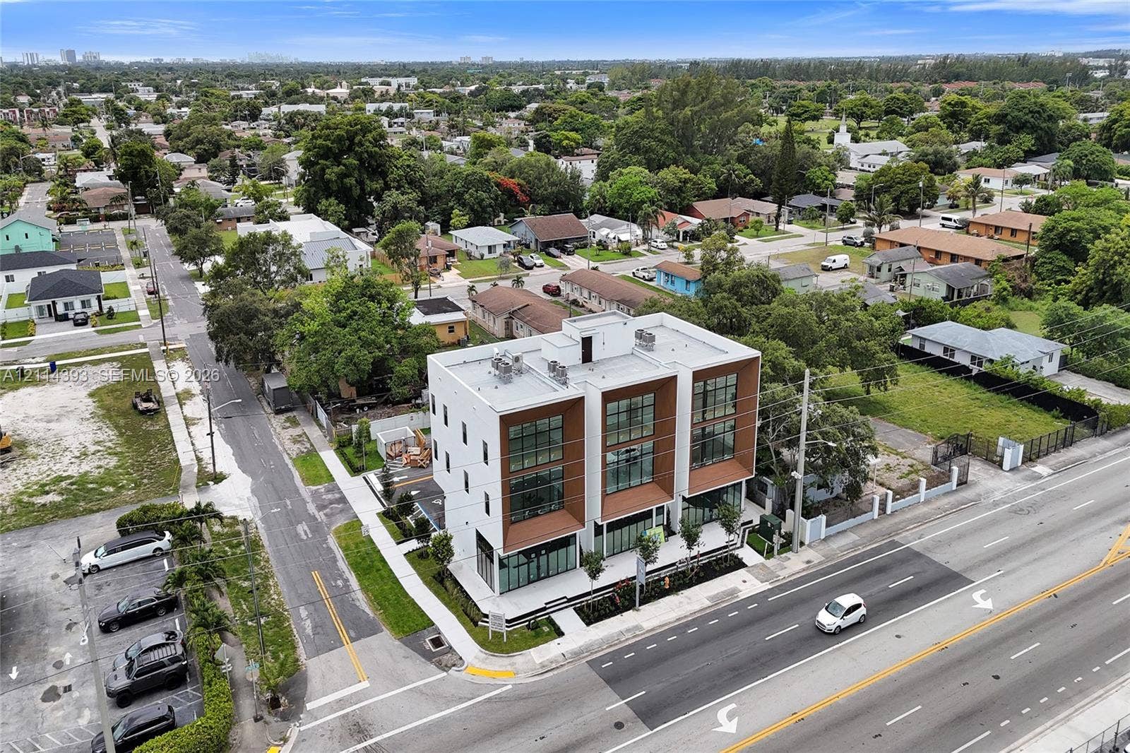 401 Pembroke Road, #202, Hallandale Beach, Hallandale Beach, FL 33009 Modern three-story multi-unit structure featuring a white facade, wood-tone recessed accents, floor-to-ceiling glass windows, and a flat roofline