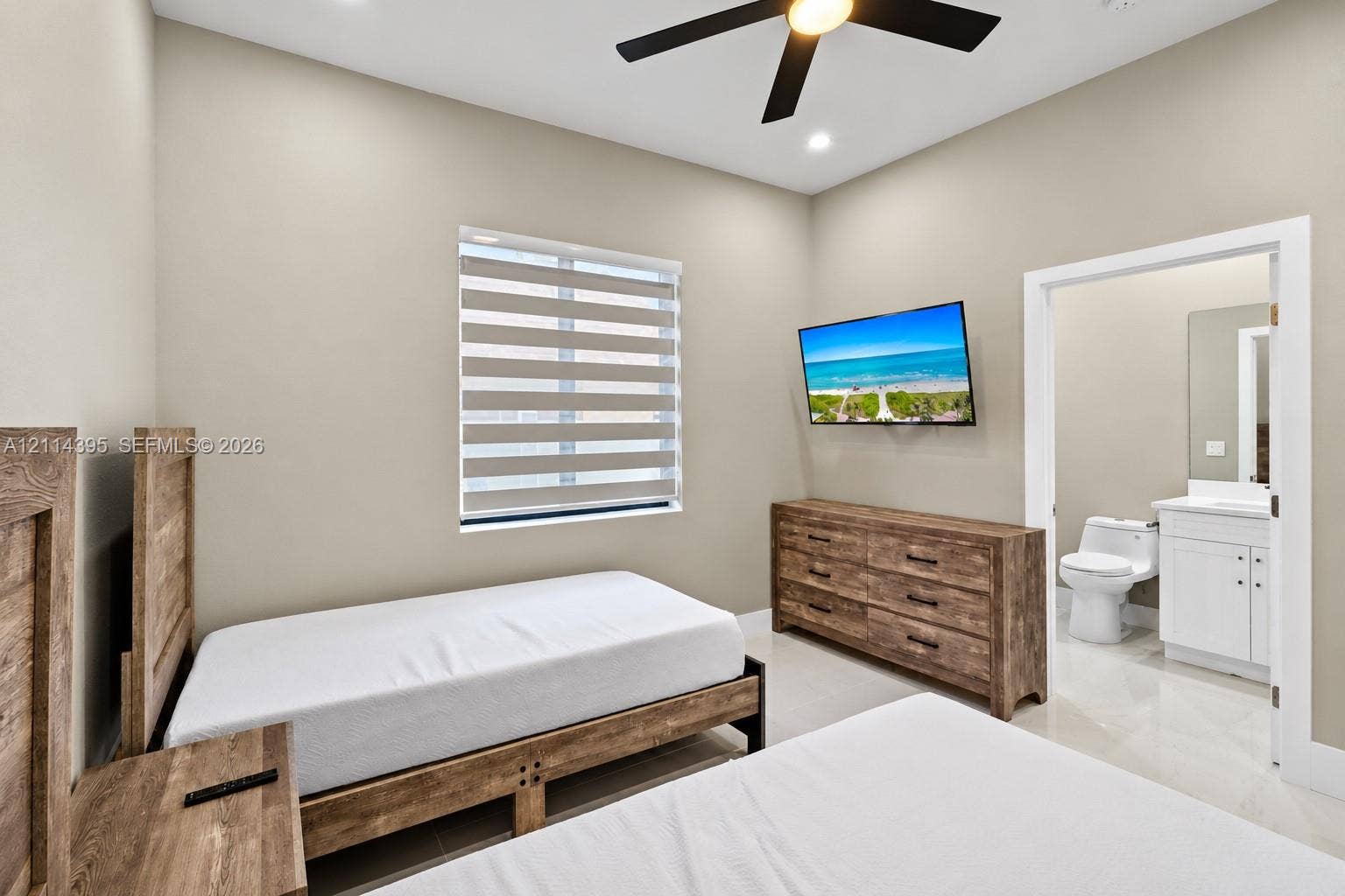 1615 NW 8th Avenue, Fort Lauderdale, FL 33311 High-ceilinged room featuring a ceiling fan, neutral wall tones, large-format tile flooring, and a window with motorized dual-layer shades