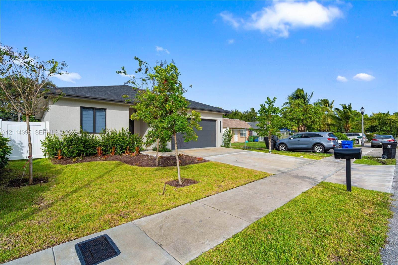 1615 NW 8th Avenue, Fort Lauderdale, FL 33311 Single-story exterior featuring a light-toned stucco facade, a dark-toned asphalt shingle roof, an attached garage, a concrete driveway, and white privacy fencing