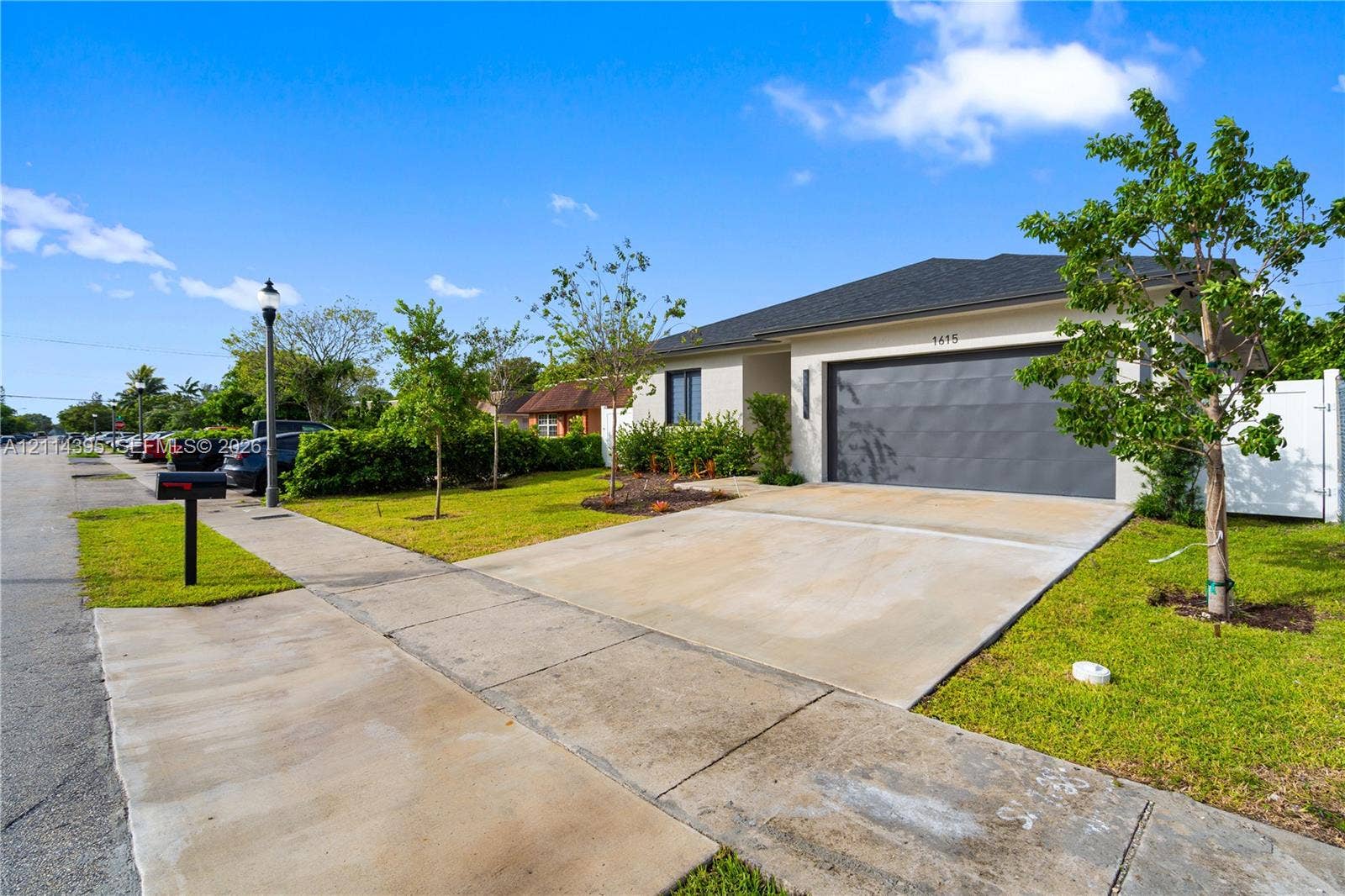 1615 NW 8th Avenue, Fort Lauderdale, FL 33311 Single-story exterior featuring a concrete driveway, two-car garage, manicured lawn, and white privacy fencing
