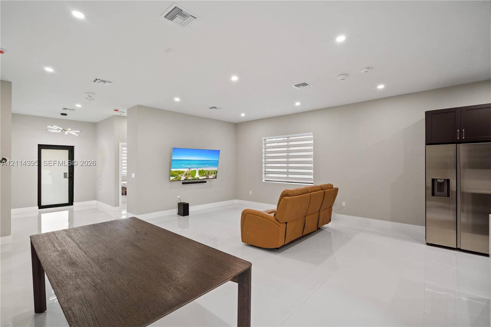 1615 NW 8th Avenue, Fort Lauderdale, FL 33311 Open-concept interior featuring large-format tile flooring, recessed ceiling lighting, roller shades, and stainless-steel refrigerator with integrated cabinetry