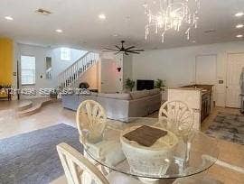 Fort Lauderdale, FL 33315 Open floor plan featuring recessed lighting, a multi-tier staircase with a white balustrade, a stone-top kitchen island, and a decorative multi-arm chandelier