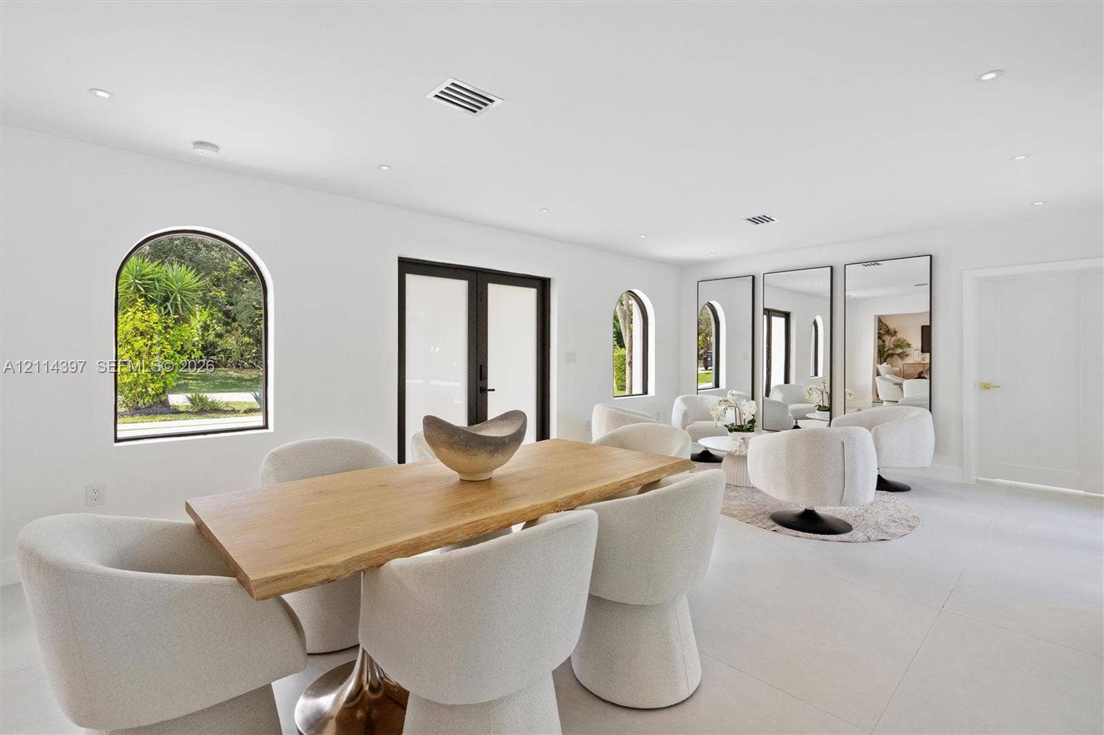 14421 SW 85th Avenue, Palmetto Bay, FL 33158 Light-filled room featuring large-format tile flooring, recessed lighting, arched window frames, and glass-paneled double doors with dark framing