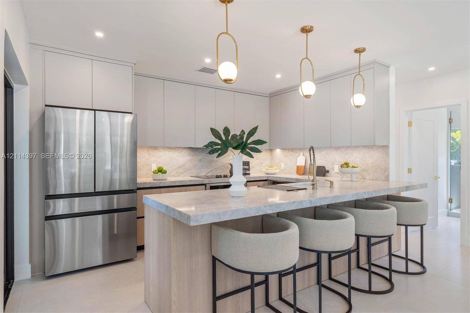 14421 SW 85th Avenue, Palmetto Bay, FL 33158 Kitchen featuring light wood-finish cabinetry, stone countertops and backsplash, stainless steel refrigerator, and three brass-finish pendant lights