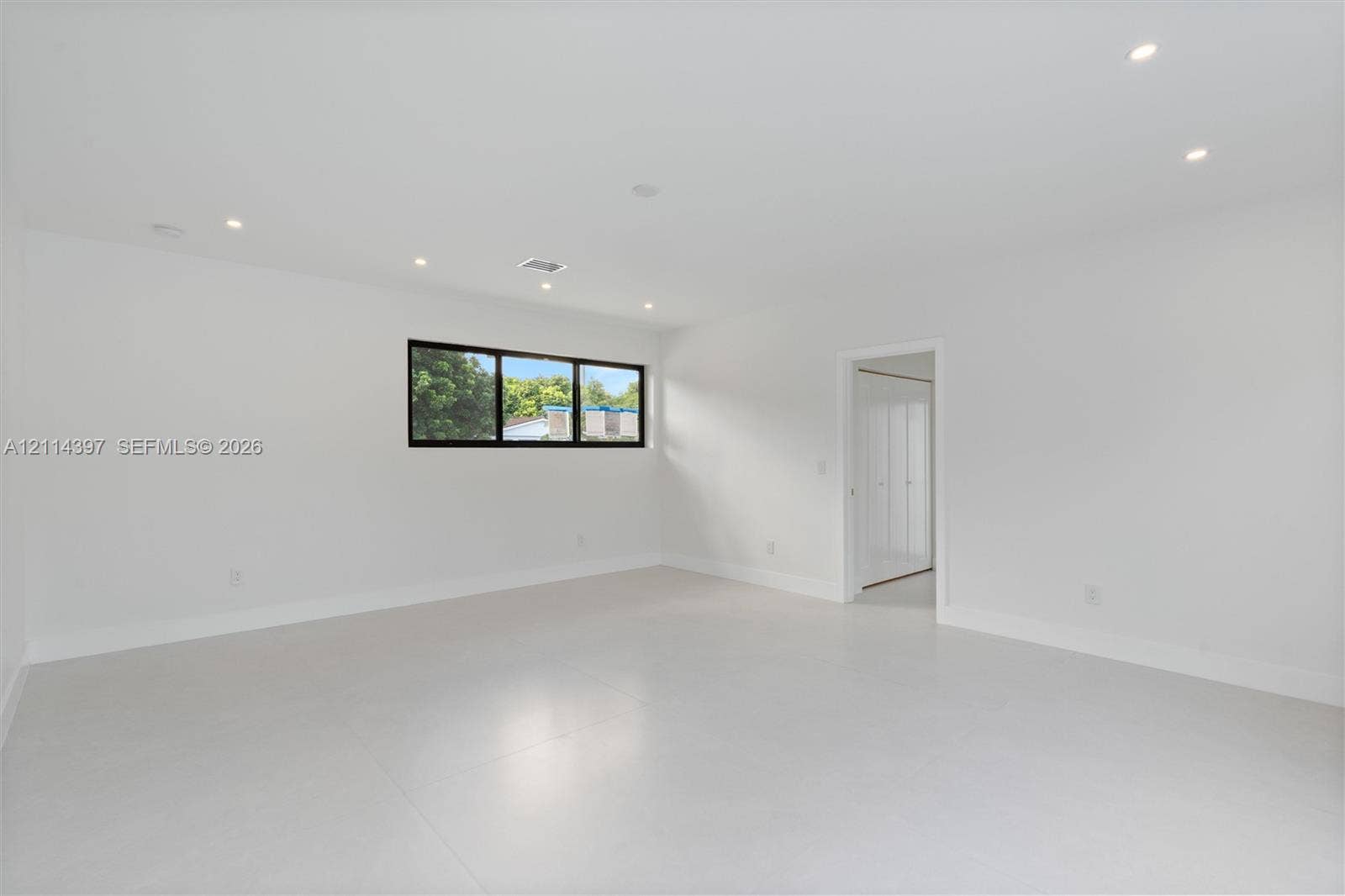 14421 SW 85th Avenue, Palmetto Bay, FL 33158 Minimalist room featuring neutral large-format tile flooring, recessed ceiling lighting, and a horizontal window with a dark frame