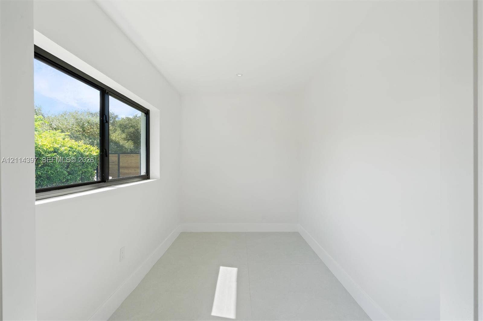 14421 SW 85th Avenue, Palmetto Bay, FL 33158 Minimalist interior space featuring large-format tile flooring, high-contrast dark-framed windows, and recessed ceiling lighting