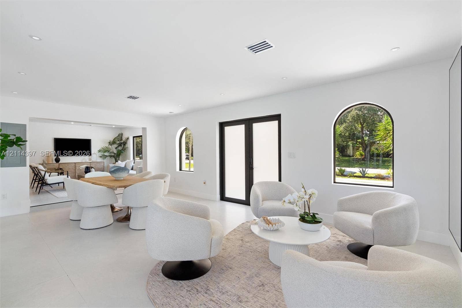 14421 SW 85th Avenue, Palmetto Bay, FL 33158 Open-concept interior featuring light-toned flooring, recessed lighting, arched window detailing, and glass-paned double doors with dark frames