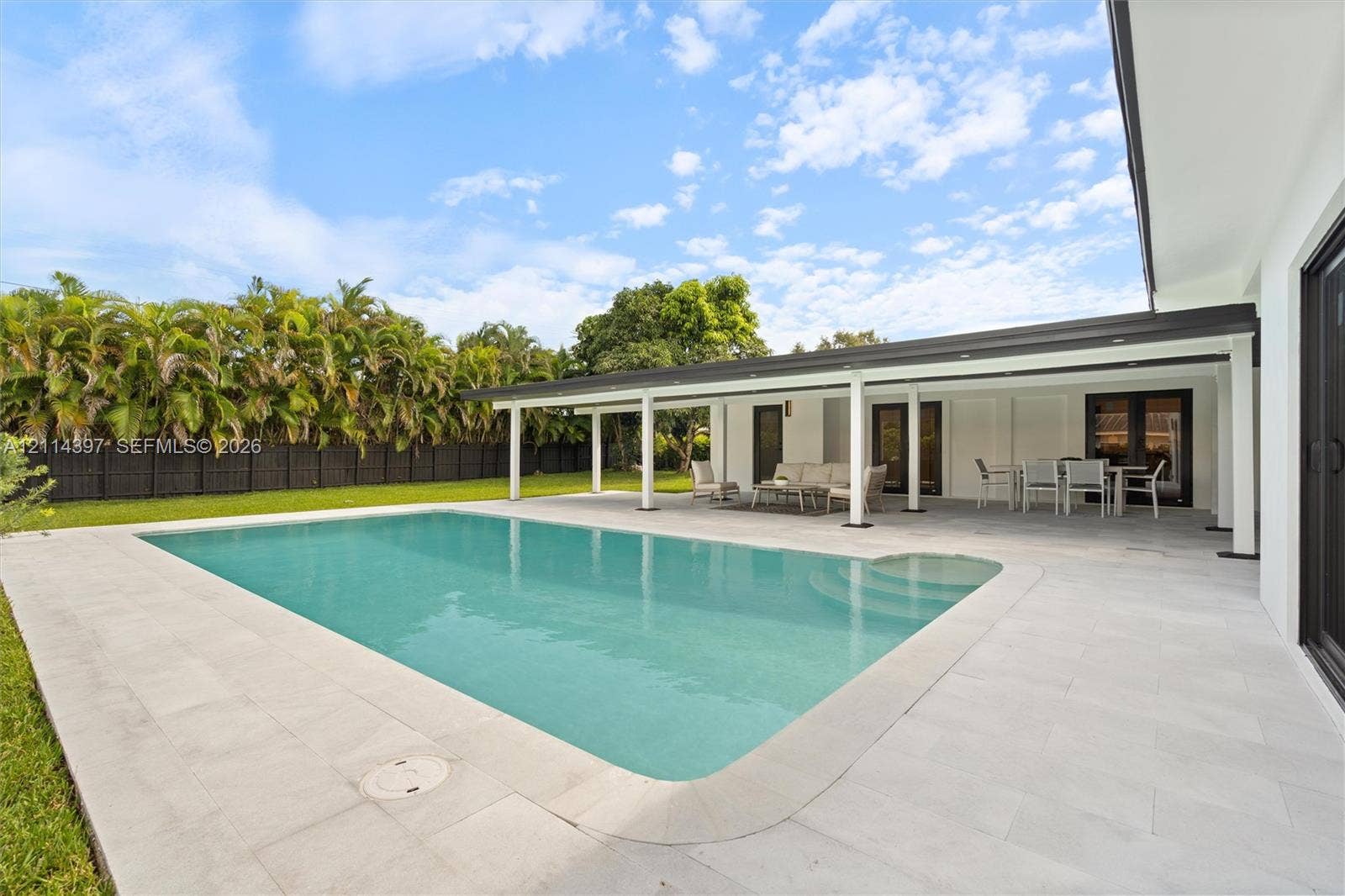 14421 SW 85th Avenue, Palmetto Bay, FL 33158 Rectangular swimming pool featuring integrated steps, expansive stone-paver decking, and a covered lanai with recessed lighting