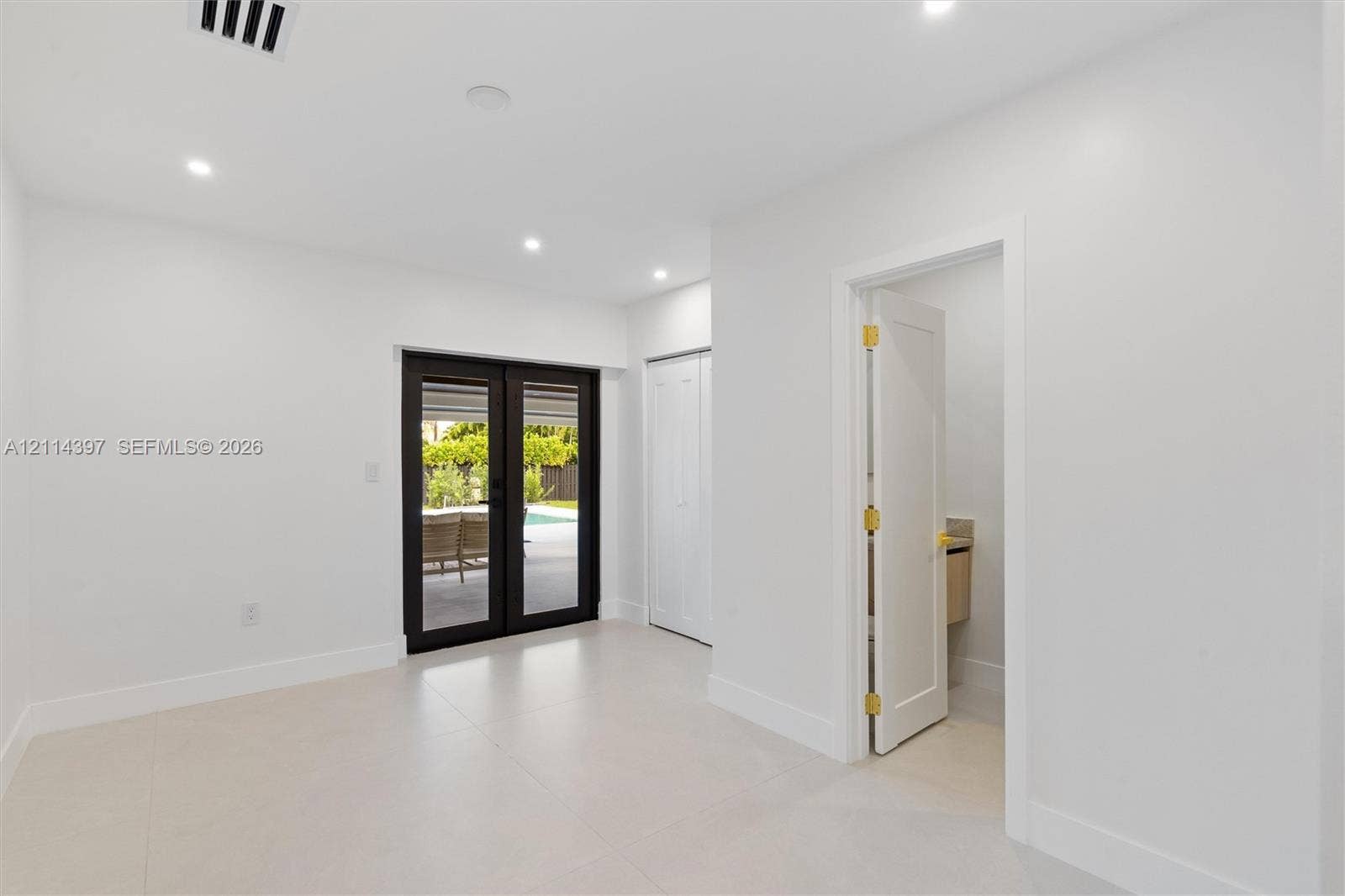14421 SW 85th Avenue, Palmetto Bay, FL 33158 Interior space featuring light-toned tile flooring, recessed ceiling lighting, a closet with double-panel doors, and black-framed French doors