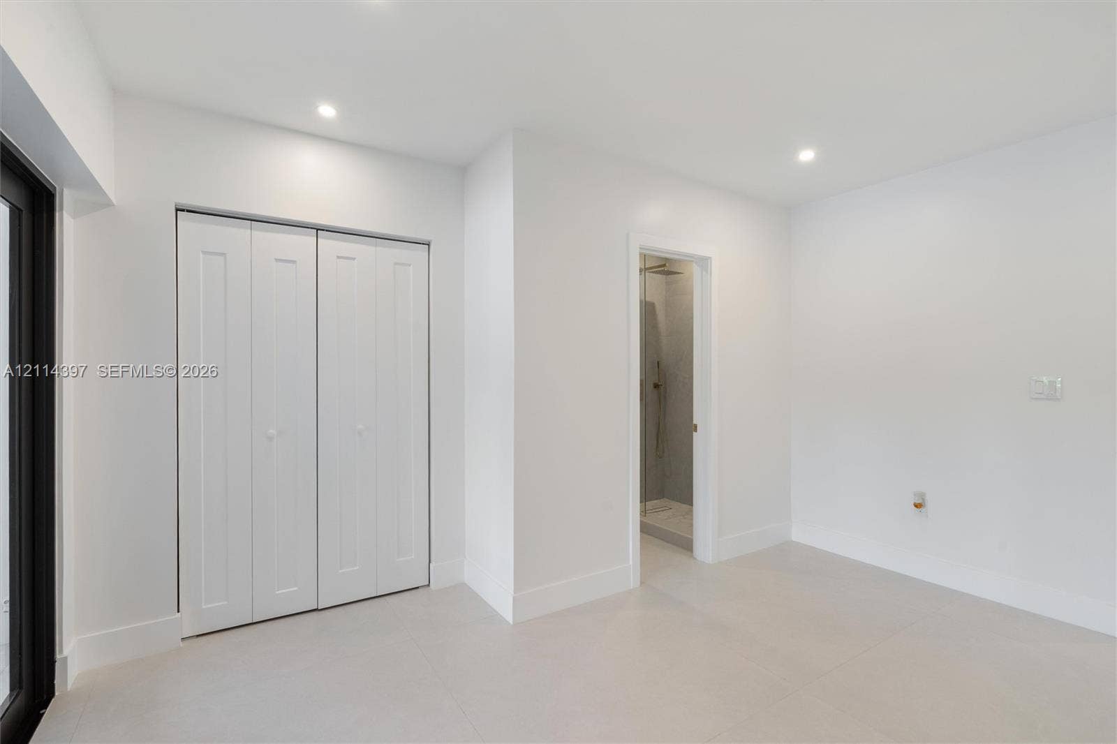 14421 SW 85th Avenue, Palmetto Bay, FL 33158 Interior space featuring large-format neutral floor tile, recessed ceiling lighting, a bi-fold closet, and a doorway revealing a tiled shower enclosure