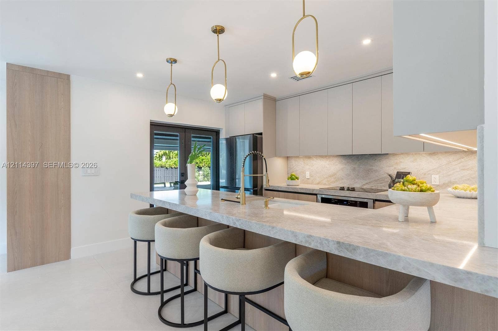 14421 SW 85th Avenue, Palmetto Bay, FL 33158 Kitchen featuring a waterfall-edge stone countertop, custom flat-panel cabinetry, gold-finish pendant lighting, and an integrated appliance package