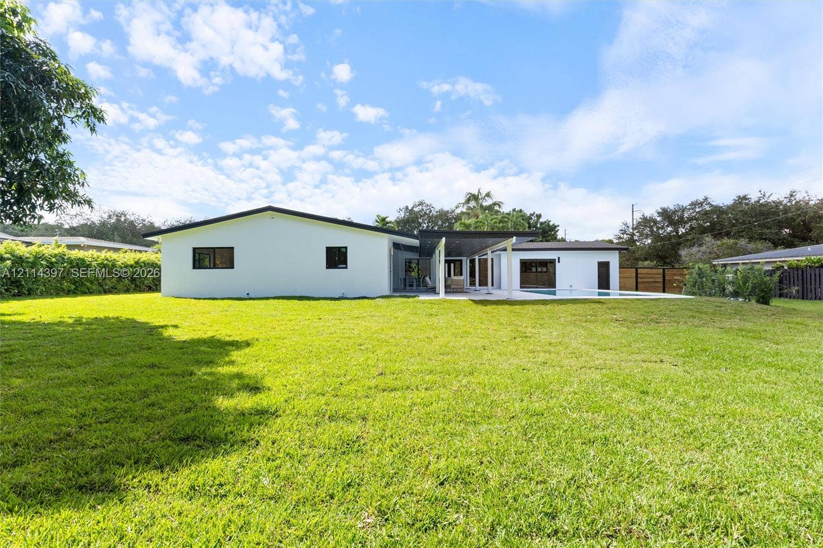 14421 SW 85th Avenue, Palmetto Bay, FL 33158 Expansive backyard featuring a sprawling lawn, swimming pool, covered patio, and perimeter privacy fencing