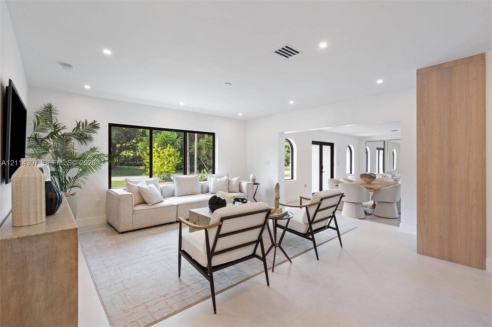 14421 SW 85th Avenue, Palmetto Bay, FL 33158 Living space featuring recessed lighting, large-format tile flooring, a wide window with dark framing, and a floor-to-ceiling wood-finish paneled wall