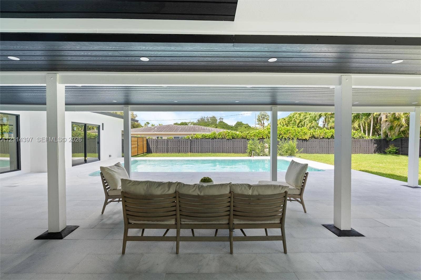 14421 SW 85th Avenue, Palmetto Bay, FL 33158 Covered patio with recessed lighting, tile flooring, and support columns, featuring a swimming pool and fenced backyard