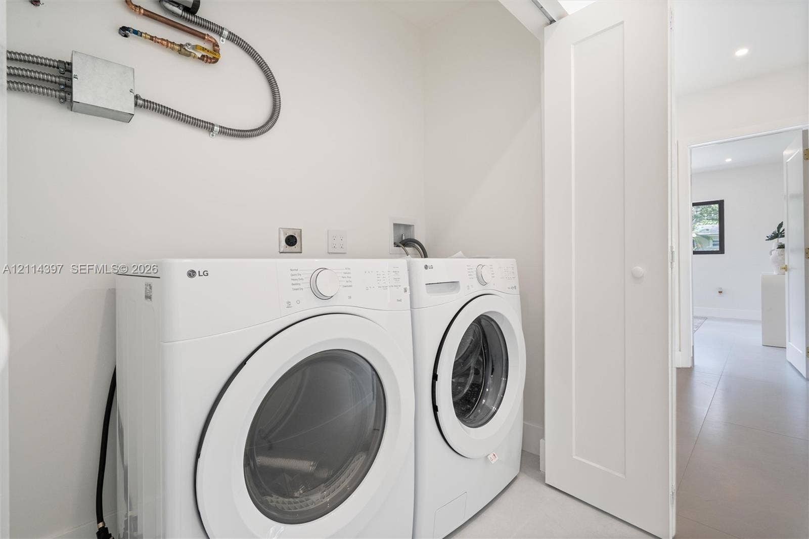 14421 SW 85th Avenue, Palmetto Bay, FL 33158 Laundry alcove featuring white front-loading appliances and neutral-toned tile flooring