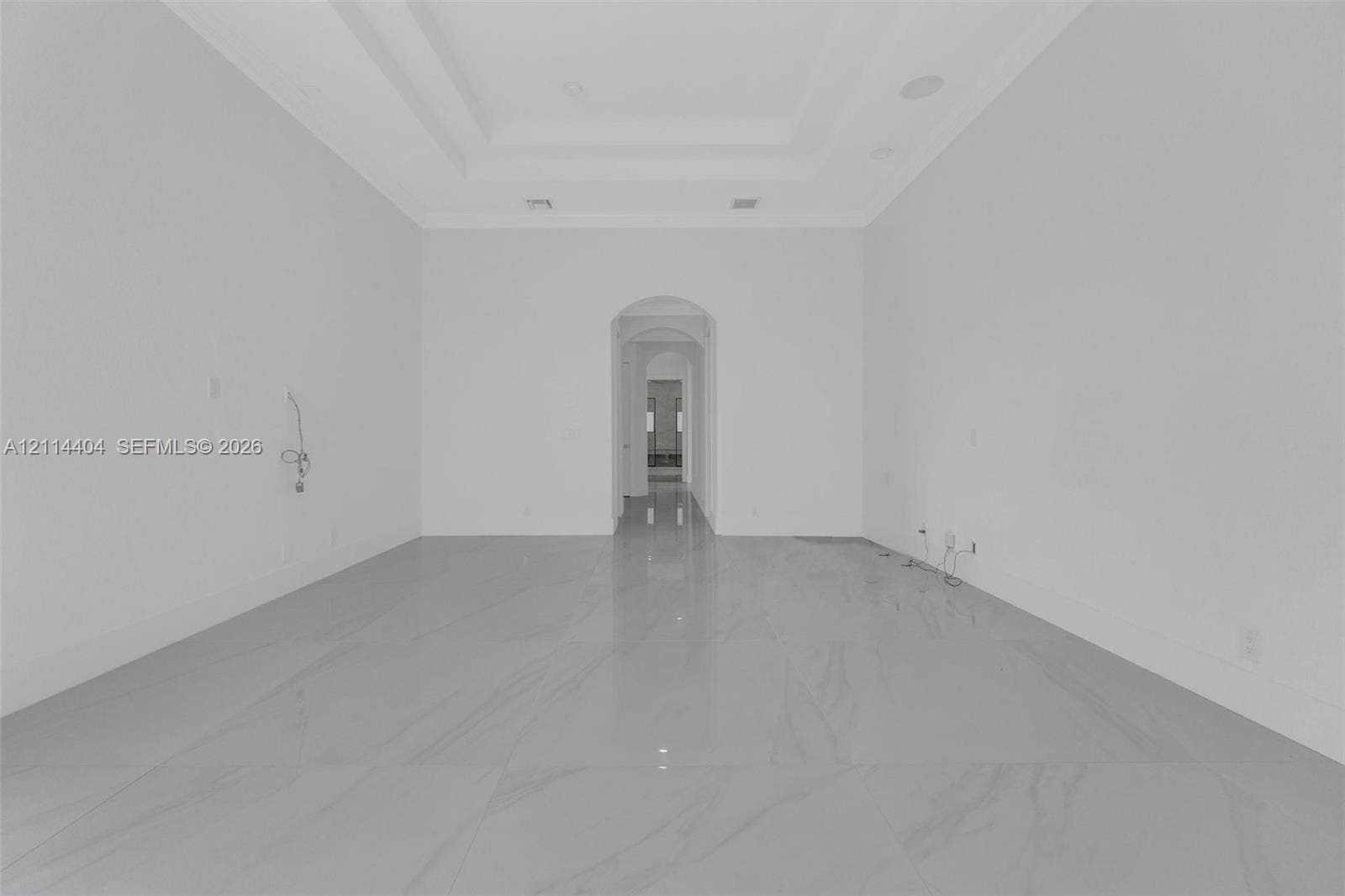 Large format tile flooring, recessed ceiling tray, and arched architectural pass-through