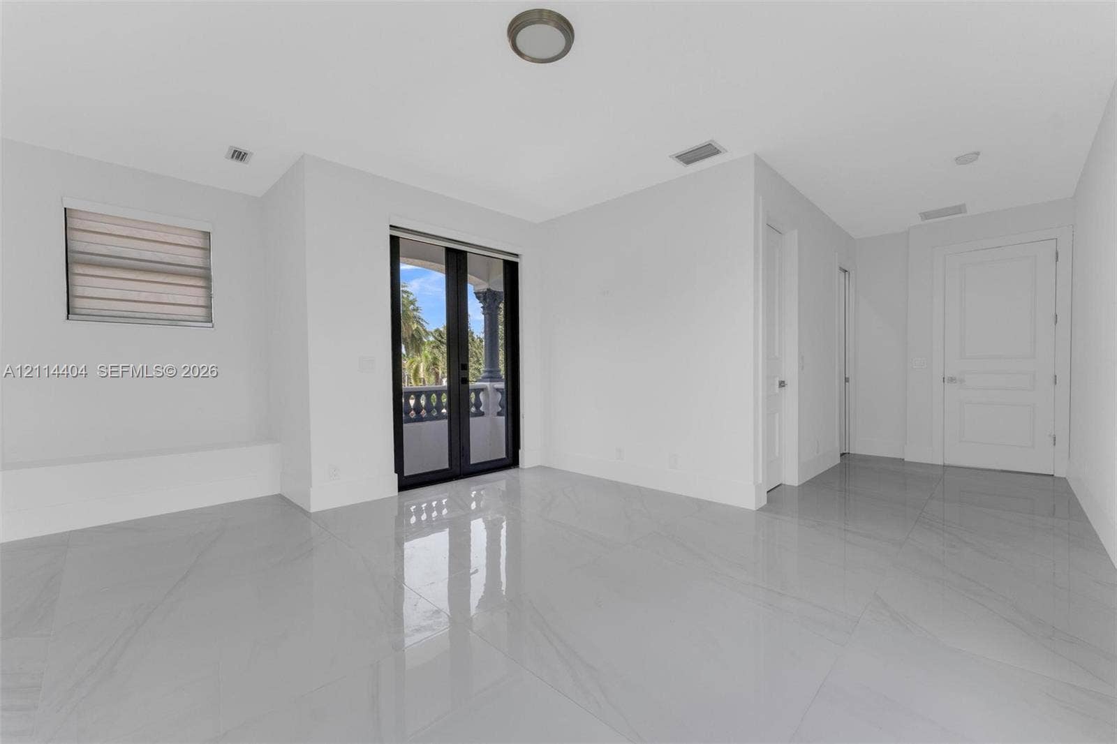 Large-format tile flooring, dual black-framed glass panel doors, recessed ceiling lighting, and solid-core interior doors
