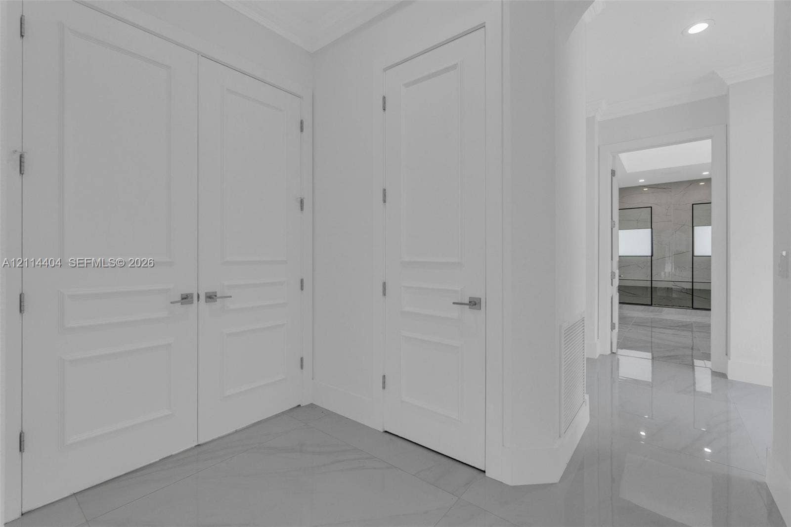 Polished large-format tile flooring, double-panel doors, and single-panel interior doors with brushed nickel hardware