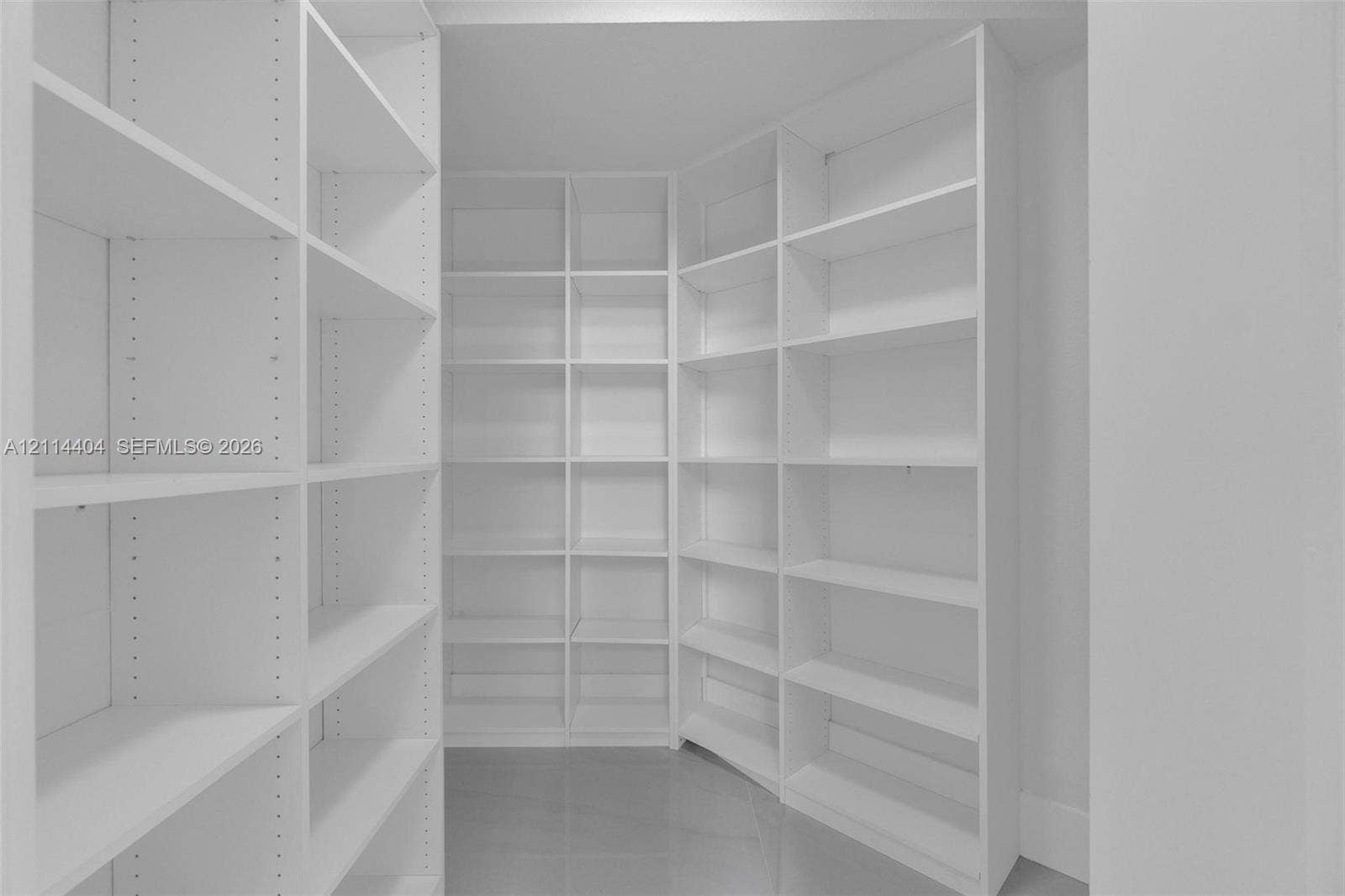 Custom white built-in shelving featuring adjustable dividers and solid surface flooring