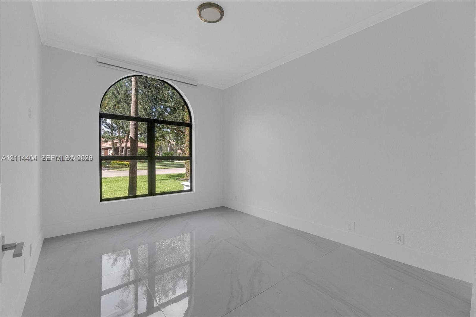 Large arched window, neutral wall palette, and polished large-format tile flooring